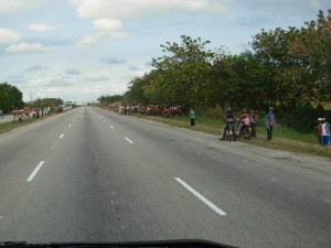 This is the one big highway in Cuba. it is sometimes used for races of horse and 2 person carriages (which are lined up on the side of the road in this photo). In the distance are spectators on the overpass. Police allow this.